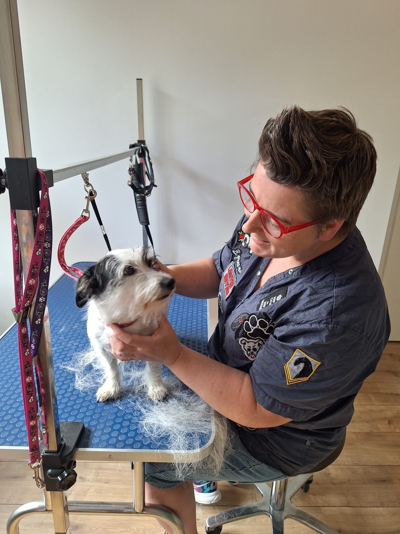 Natasja aan de trimtafel met een klein wit hondje op de blauwe mat
